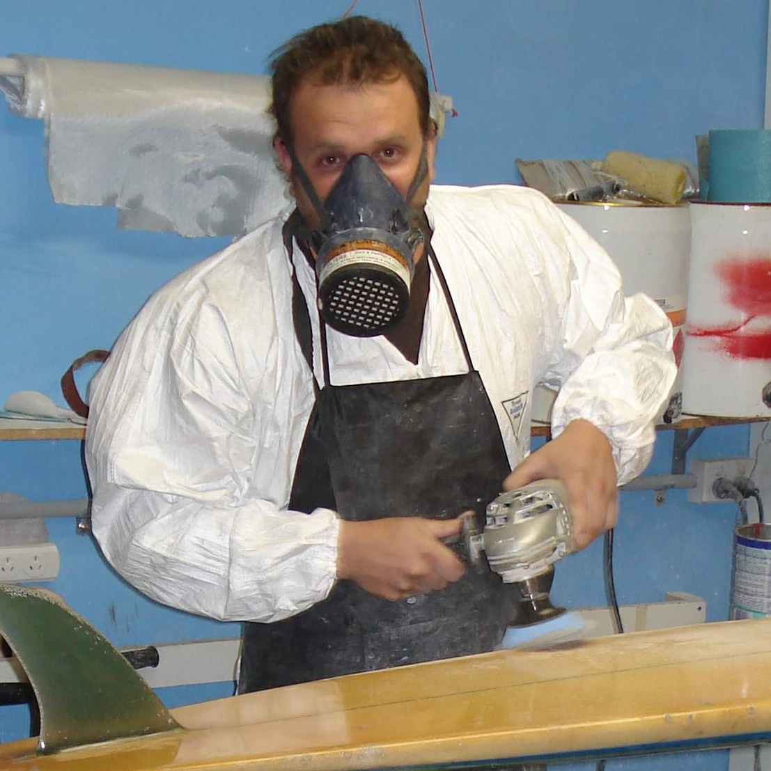 Zachary Koniaras shaping a surfboard with a grinder